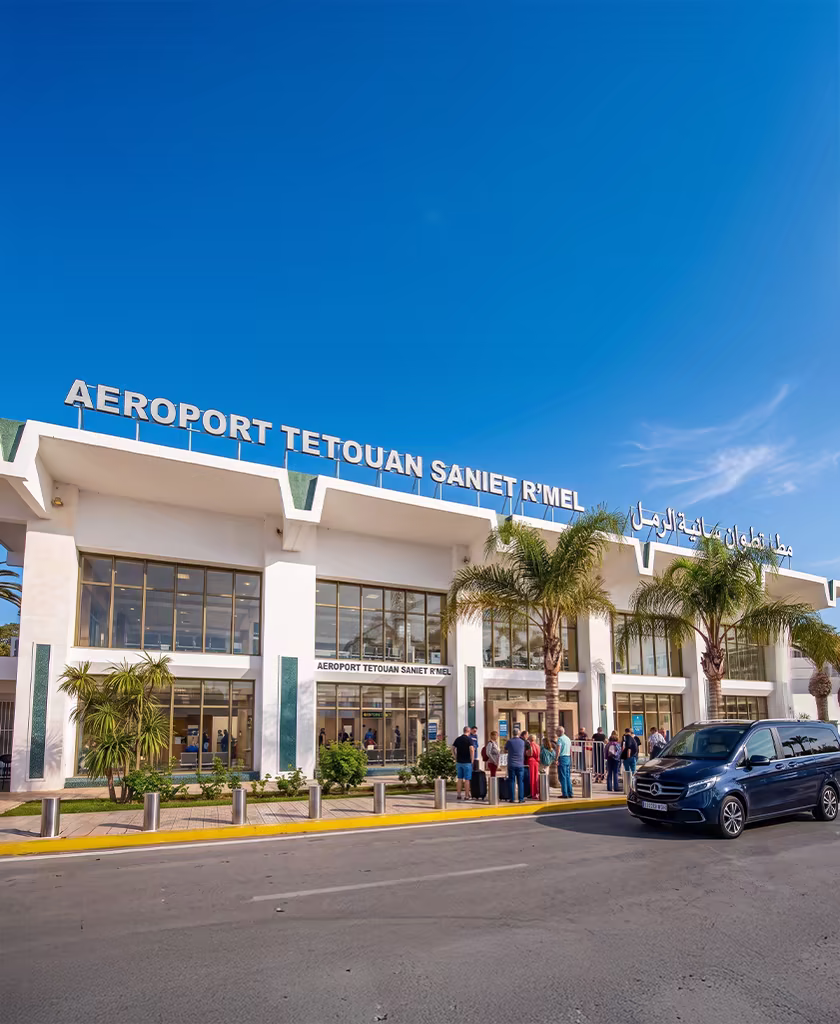 Façade du terminal de l'aéroport de Tétouan-Saniat R'mel (TTU) avec un van de transfert et des voyageurs