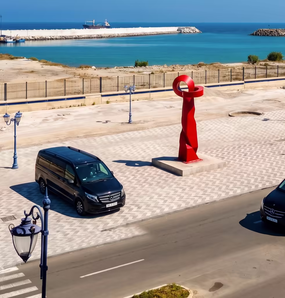 Berline de prestige avec chauffeur privé devant les célèbres murailles blanches d'Asilah